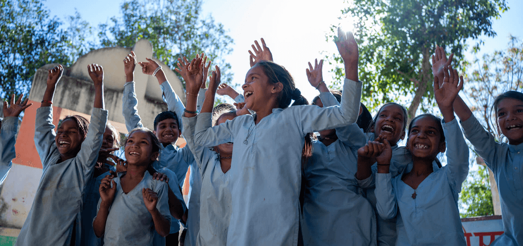 Joyful Indian school children celebrating with hands raised