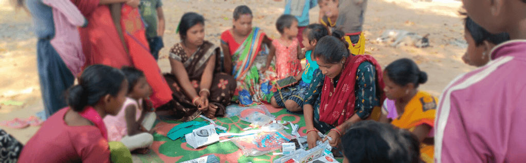 A group of Indian women sitting in a circle outdoors and sharing skills during a collaborative workshop session